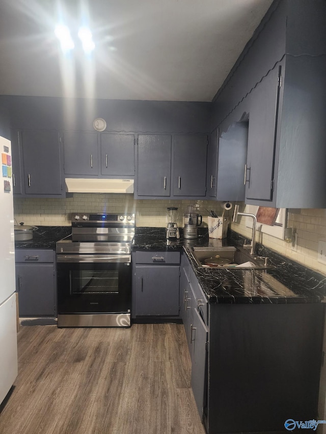 kitchen featuring electric range, dark wood-style flooring, a sink, under cabinet range hood, and backsplash