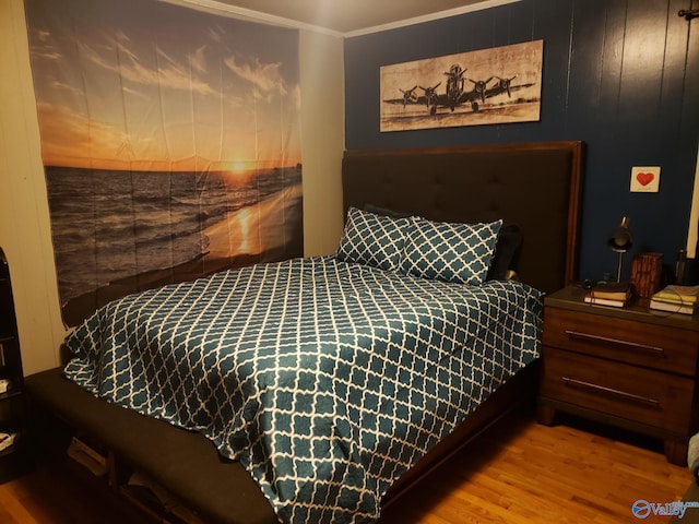 bedroom with wood finished floors and ornamental molding