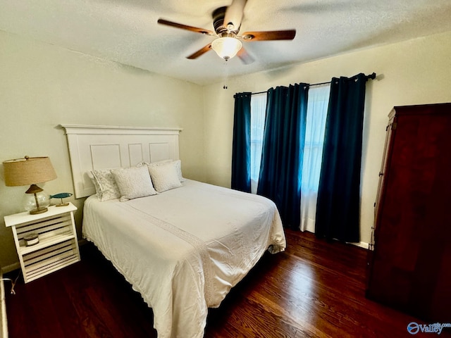 bedroom with a textured ceiling, ceiling fan, and dark hardwood / wood-style floors