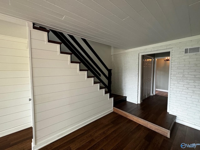 stairs with hardwood / wood-style flooring and brick wall