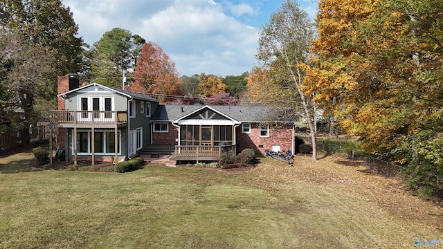 back of property featuring a lawn, a deck, and a sunroom