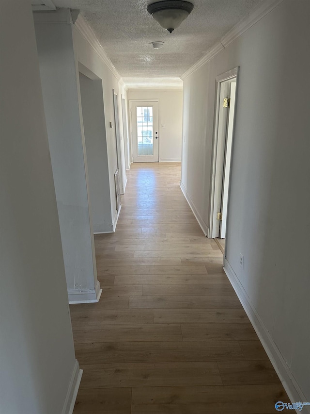 hallway featuring ornamental molding, a textured ceiling, and light hardwood / wood-style floors