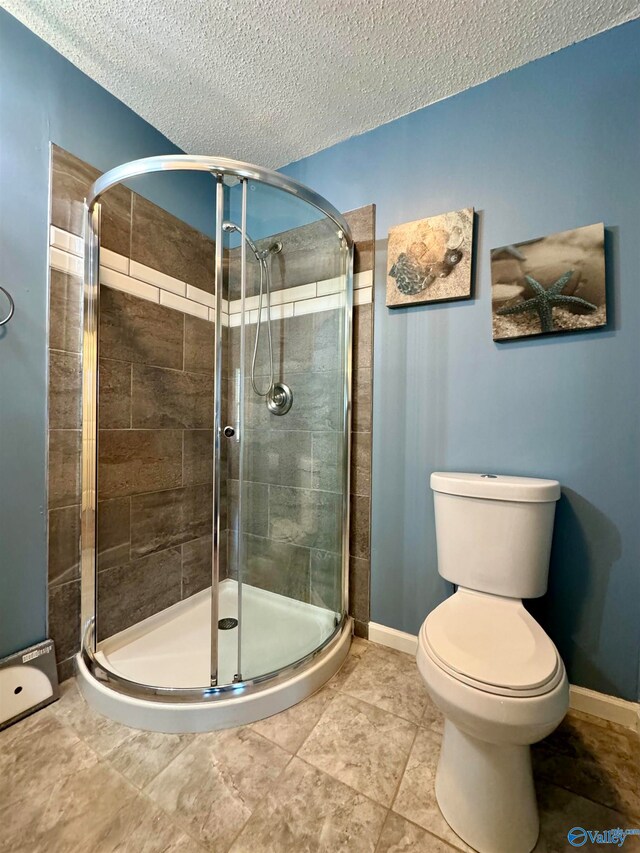 bathroom with toilet, a stall shower, baseboards, and a textured ceiling