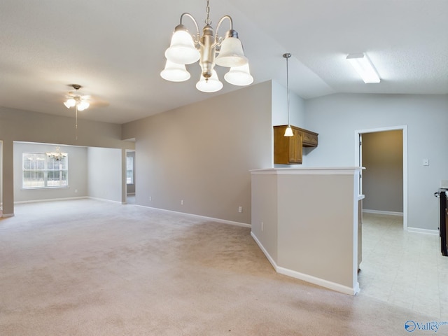 carpeted spare room featuring ceiling fan with notable chandelier and vaulted ceiling