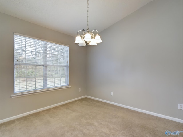 carpeted empty room featuring a chandelier