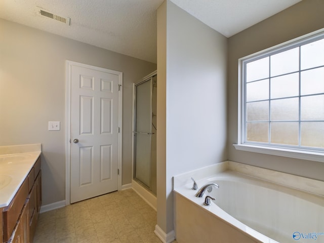 bathroom with vanity, independent shower and bath, and a textured ceiling