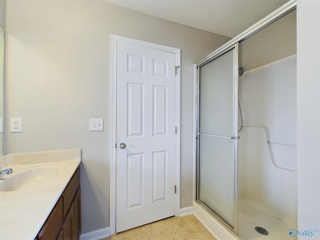 bathroom featuring vanity, a textured ceiling, and a shower with door