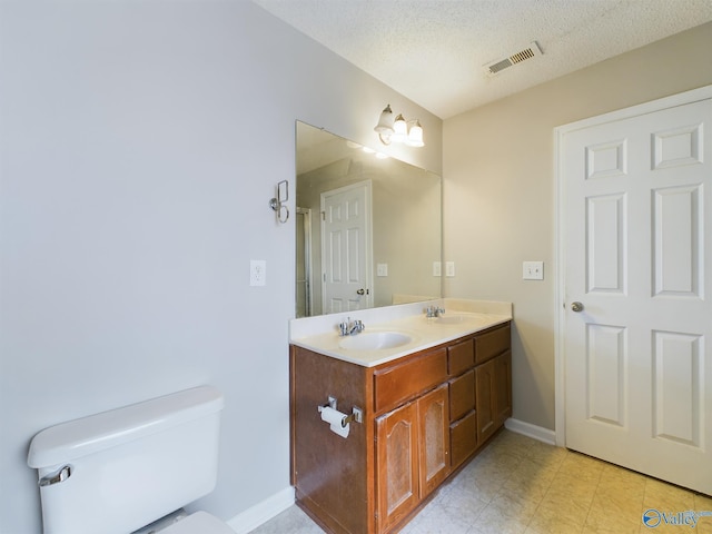 bathroom featuring vanity, toilet, and a textured ceiling