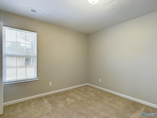 empty room with light carpet and a textured ceiling