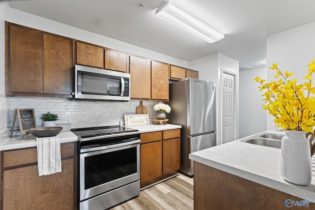 kitchen featuring sink, light hardwood / wood-style flooring, stainless steel appliances, and tasteful backsplash