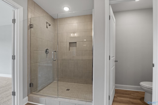 bathroom featuring a shower with door, hardwood / wood-style floors, and toilet