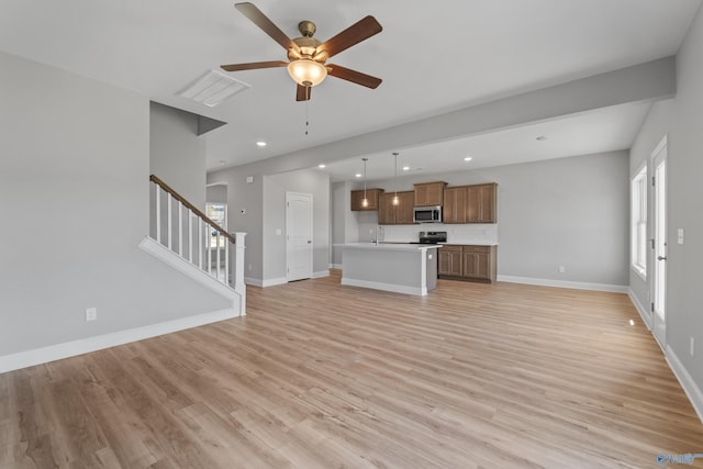 unfurnished living room with ceiling fan, sink, and light wood-type flooring