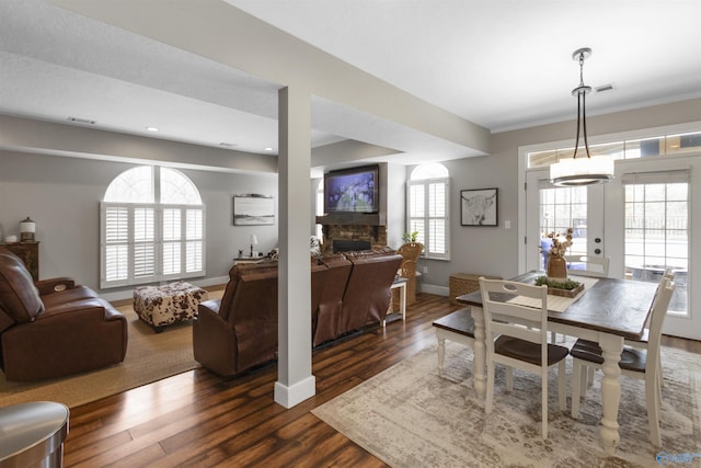 dining area featuring crown molding, a stone fireplace, and dark hardwood / wood-style flooring