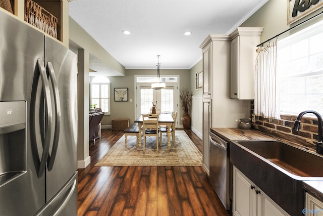 kitchen with sink, dark wood-type flooring, stainless steel appliances, ornamental molding, and decorative light fixtures