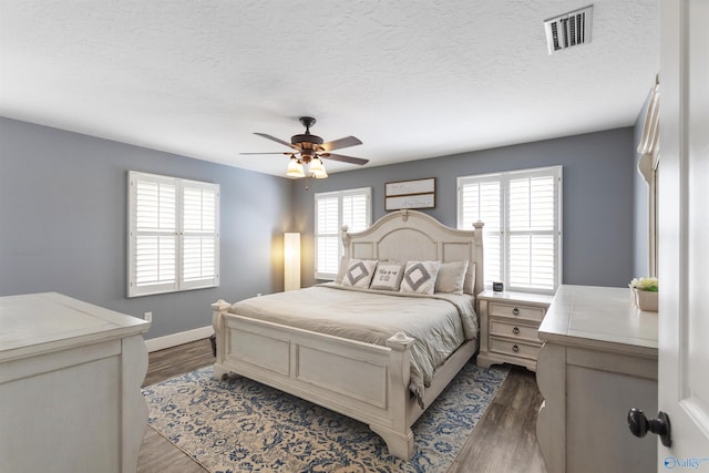 bedroom featuring multiple windows, ceiling fan, a textured ceiling, and dark hardwood / wood-style flooring