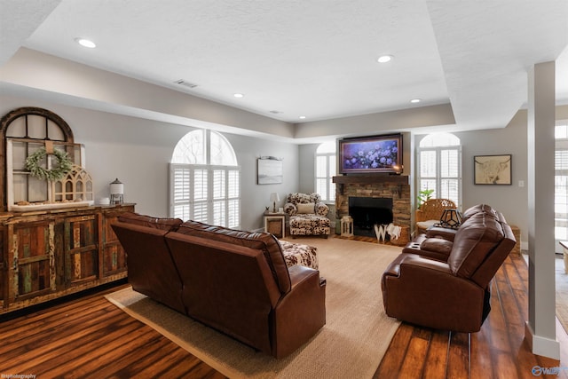 living room with dark hardwood / wood-style flooring, a fireplace, a raised ceiling, and a textured ceiling