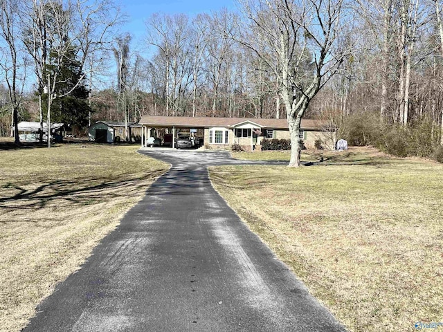 view of front of home with a carport, a front yard, and driveway