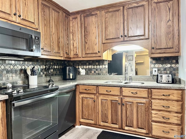 kitchen with appliances with stainless steel finishes, brown cabinets, and a sink