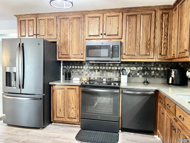 kitchen with stainless steel appliances, brown cabinetry, and light wood-style flooring