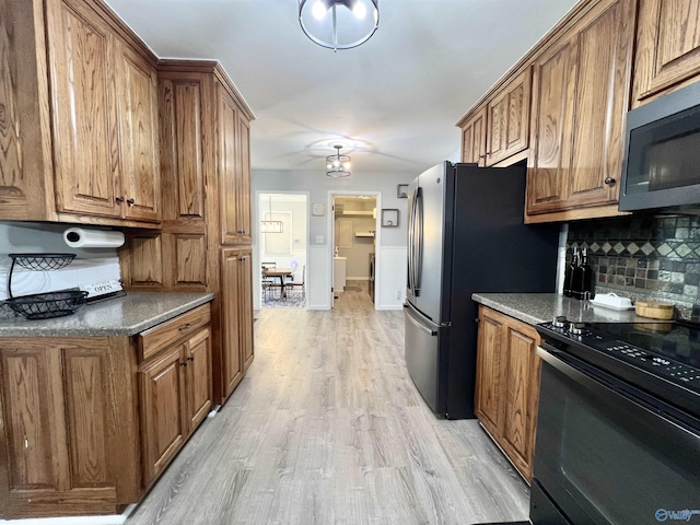 kitchen with stainless steel appliances, backsplash, brown cabinets, and light wood-style flooring