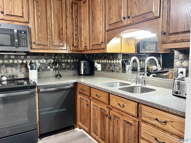 kitchen with stainless steel appliances, brown cabinets, a sink, and backsplash