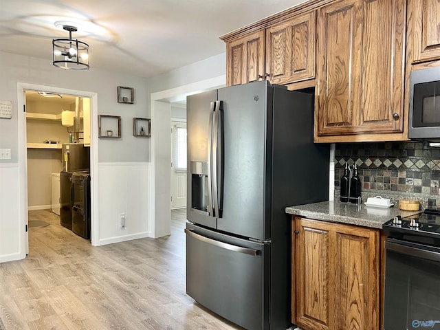 kitchen featuring stainless steel appliances, washing machine and dryer, and brown cabinetry