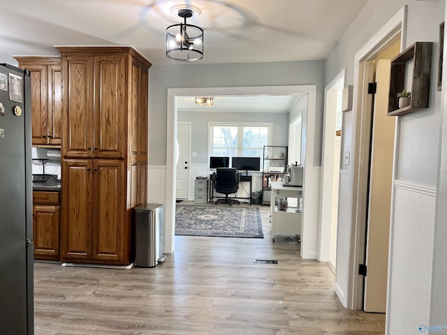 interior space with a wainscoted wall, light wood finished floors, and a notable chandelier