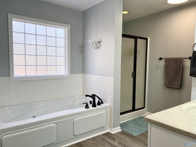 full bathroom with a wealth of natural light, a garden tub, a shower stall, and wood finished floors