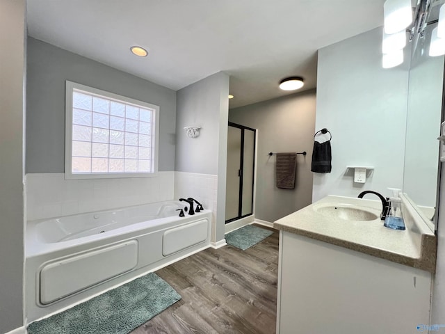 full bath featuring a stall shower, vanity, wood finished floors, baseboards, and a bath