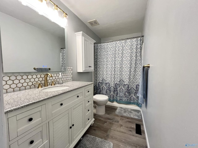 full bath featuring toilet, wood finished floors, visible vents, vanity, and decorative backsplash