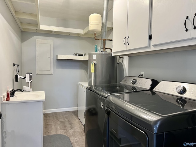 clothes washing area featuring gas water heater, washing machine and dryer, light wood-style flooring, cabinet space, and electric panel