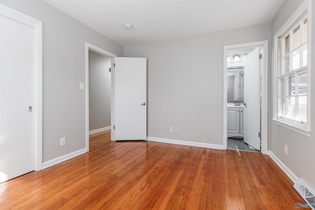 unfurnished bedroom featuring light wood-type flooring, multiple windows, and visible vents