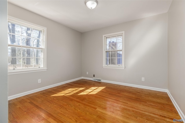 empty room featuring visible vents, baseboards, and wood finished floors