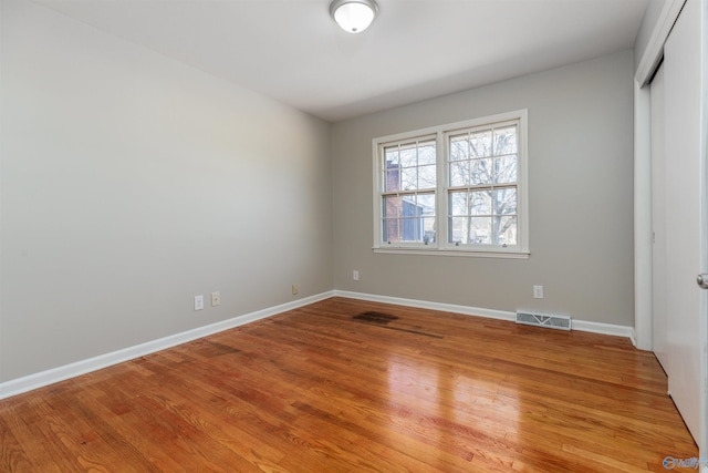 unfurnished bedroom featuring a closet, visible vents, baseboards, and wood finished floors