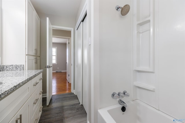 bathroom featuring shower / bathing tub combination, vanity, baseboards, and wood finished floors