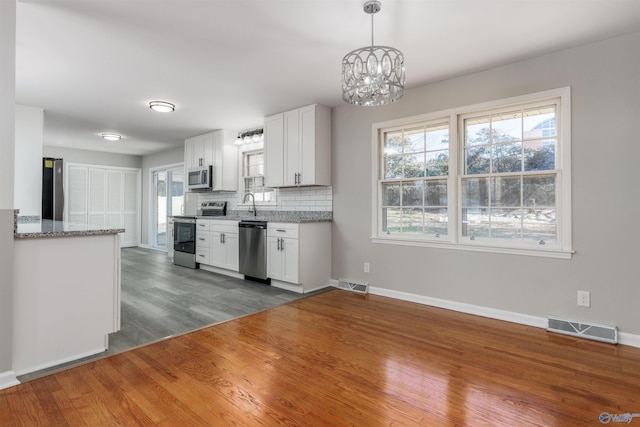 kitchen featuring visible vents, appliances with stainless steel finishes, white cabinetry, pendant lighting, and backsplash