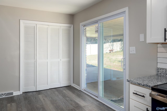 doorway to outside featuring dark wood-type flooring, visible vents, and baseboards