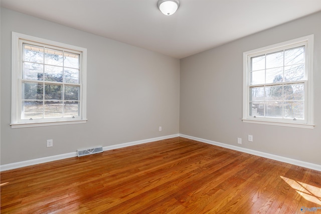 empty room with visible vents, baseboards, and wood finished floors