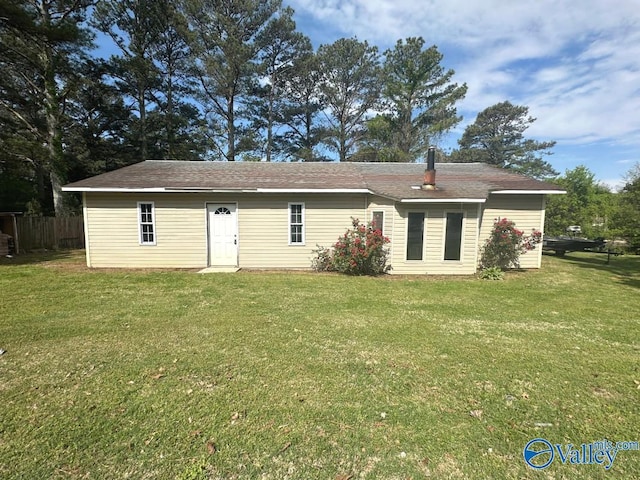 rear view of house featuring roof with shingles and a yard