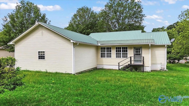 rear view of property featuring metal roof and a lawn