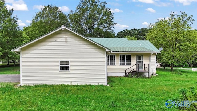 rear view of house with a lawn and metal roof