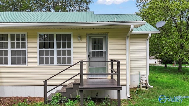 view of exterior entry with metal roof and a lawn