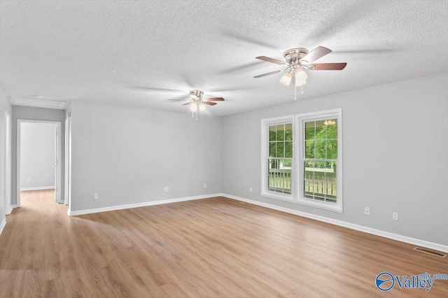 empty room with ceiling fan, a textured ceiling, light wood-type flooring, and visible vents