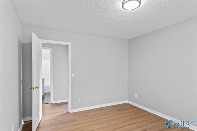 interior space featuring baseboards, a textured ceiling, and wood finished floors