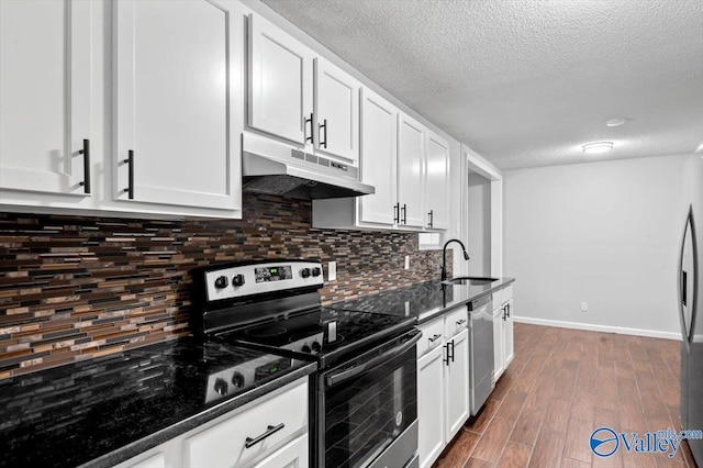 kitchen with a textured ceiling, under cabinet range hood, a sink, white cabinetry, and appliances with stainless steel finishes