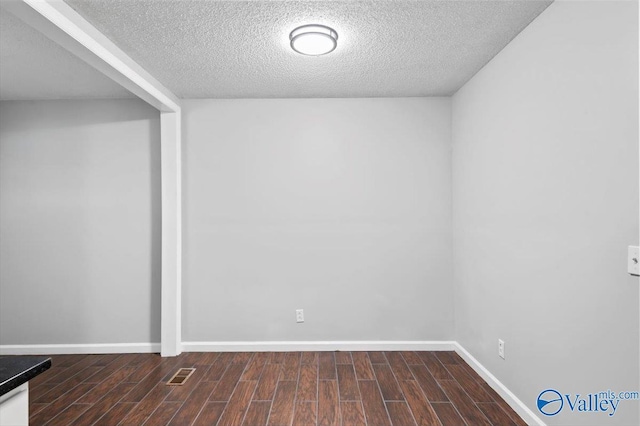 interior space featuring baseboards, visible vents, a textured ceiling, and wood finished floors