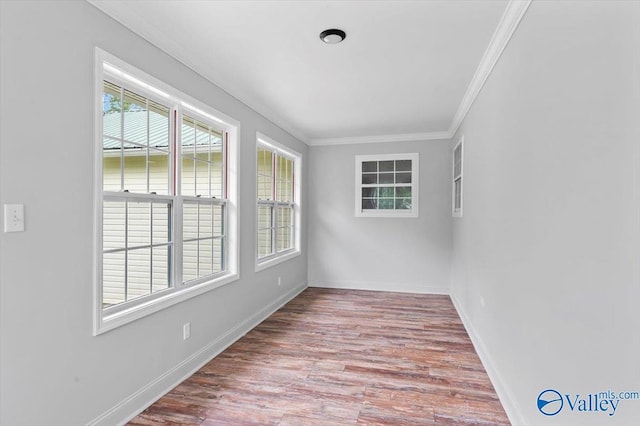 unfurnished room with ornamental molding, baseboards, and wood finished floors