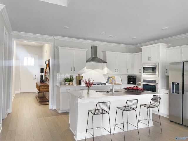 208 Fallow Cir, Madison, AL 35757 - kitchen with appliances with stainless steel finishes, wall chimney range hood, a breakfast bar area, a center island with sink, and light wood-type flooring