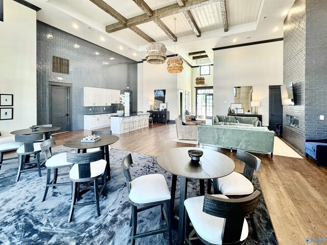 208 Fallow Cir, Madison, AL 35757 - living room featuring a high ceiling, wood finished floors, beamed ceiling, a fireplace, and a chandelier