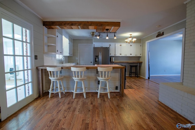 kitchen featuring a peninsula, white cabinets, light countertops, stainless steel refrigerator with ice dispenser, and open shelves